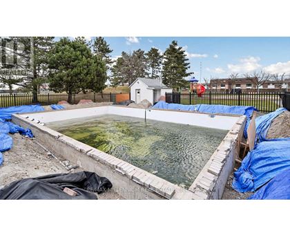 A construction site with a pool under construction surrounded by blue tarps.