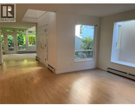 A spacious room with wooden floors and a large window.