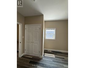 A room with a white door and a window with a view of a fence and trees.