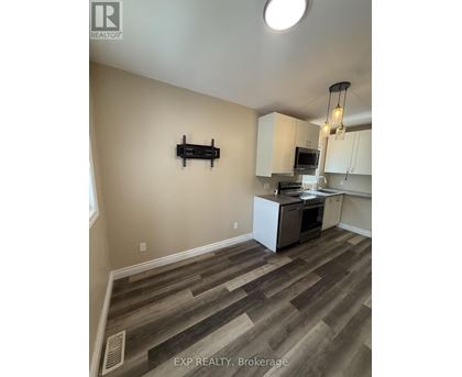 A kitchen with white cabinets and a wooden floor.