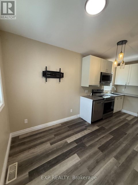 A kitchen with white cabinets and a wooden floor.