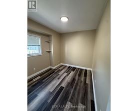 A room with wooden flooring and a window with blinds.