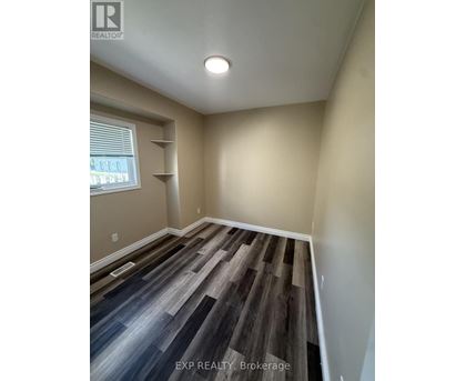 A room with wooden flooring and a window with blinds.