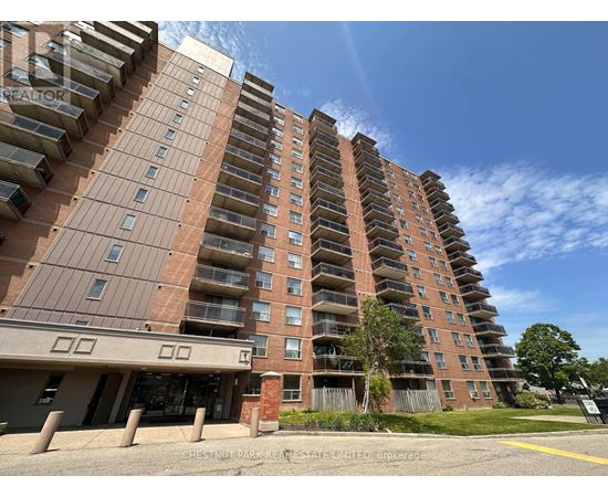 A tall apartment building with a parking lot in front.