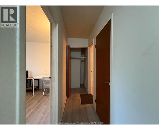 A hallway with a table and chairs on the left and a door on the right.