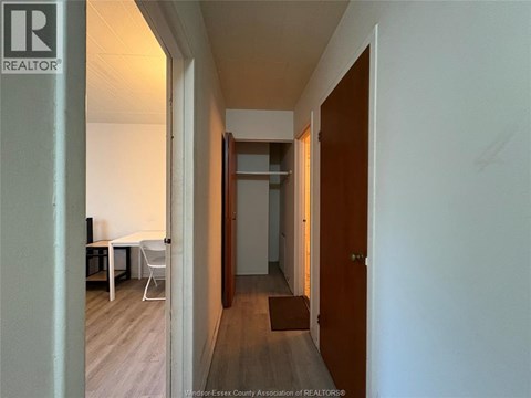A hallway with a table and chairs on the left and a door on the right.