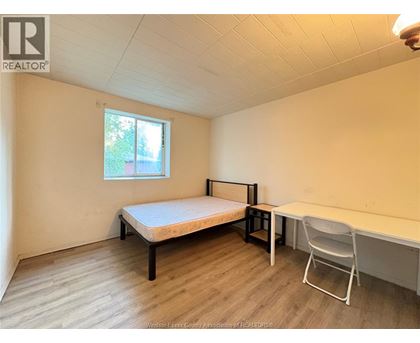 A bedroom with a bed, desk, and chair.