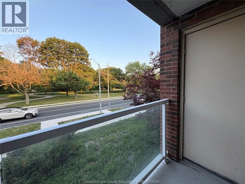 A balcony with a view of a street and trees.