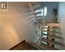 A wooden spiral staircase in a room with a plant on the landing.