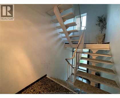 A wooden spiral staircase in a room with a plant on the landing.