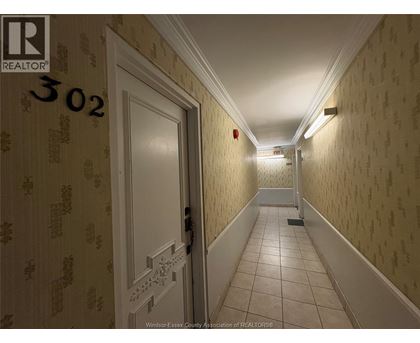 A hallway with a door on the left and a fire extinguisher on the wall.