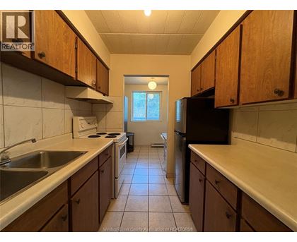A kitchen with wooden cabinets and a black refrigerator.