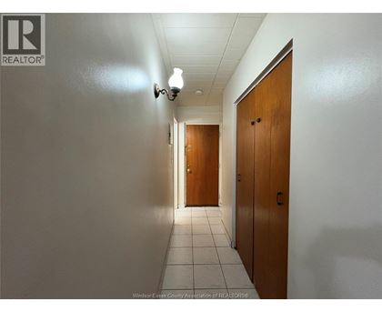 A hallway with two doors at the end and a light on the wall.