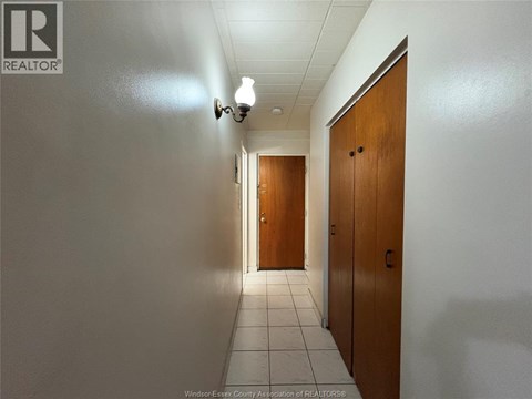 A hallway with two doors at the end and a light on the wall.