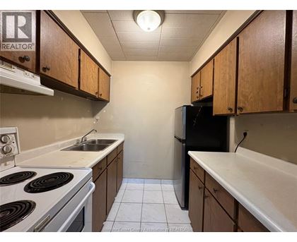 A kitchen with a stove top oven, sink, and refrigerator.