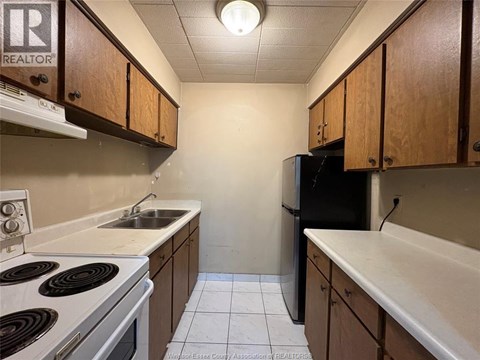 A kitchen with a stove top oven, sink, and refrigerator.