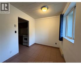 A room with a brown tile floor and a window with a blue curtain.