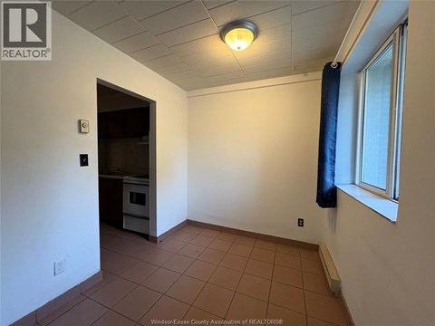 A room with a brown tile floor and a window with a blue curtain.