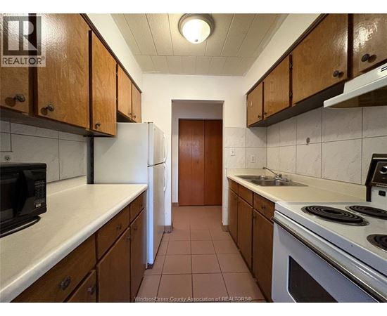 A kitchen with white appliances and brown cabinets.
