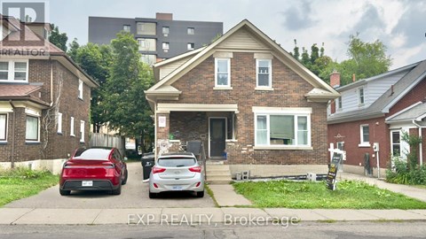 A house with a red car and a white car parked in front.