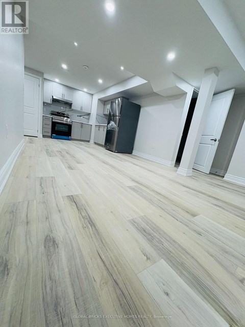 A spacious room with wooden flooring and white walls.