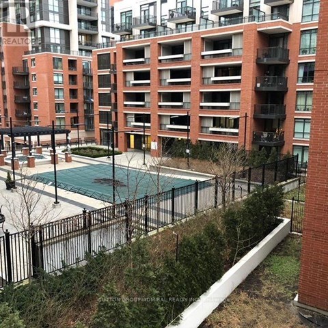 A pool surrounded by a black fence in front of a red brick building.