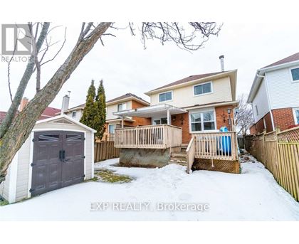 A snow-covered backyard with a wooden deck and a detached house.
