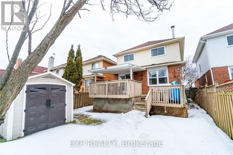 A snow-covered backyard with a wooden deck and a detached house.