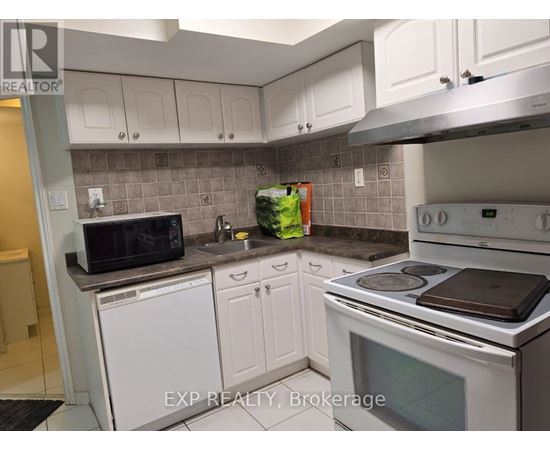 A kitchen with white cabinets and a white stove top oven.