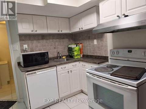 A kitchen with white cabinets and a white stove top oven.
