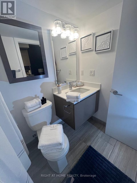A bathroom with a toilet, sink, and mirror.
