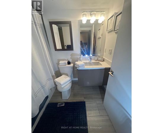 A bathroom with a toilet, sink, and mirror.