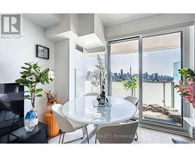 A modern dining room with a glass table and chairs, a vase of flowers, and a view of the city skyline through the window.