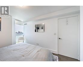 A bedroom with a bed, a chair, and a mirror on the wall.