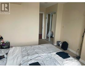 A bedroom with a bed, a nightstand, a backpack, and a mirror.