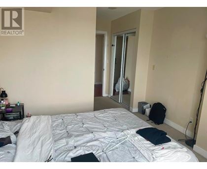 A bedroom with a bed, a nightstand, a backpack, and a mirror.