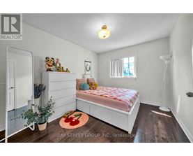 A bedroom with a bed, a window, and a rug with a red design on it.
