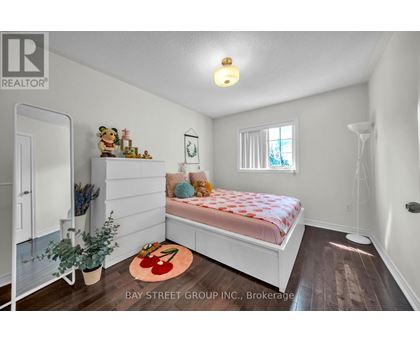 A bedroom with a bed, a window, and a rug with a red design on it.
