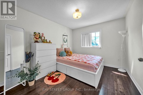 A bedroom with a bed, a window, and a rug with a red design on it.
