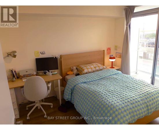 A bedroom with a bed, desk, and chair.