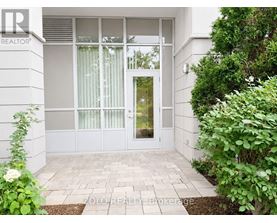 A white house with a glass door and a brick walkway leading to it.