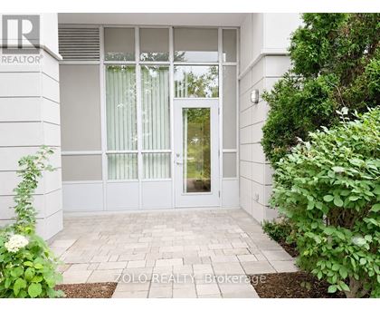 A white house with a glass door and a brick walkway leading to it.