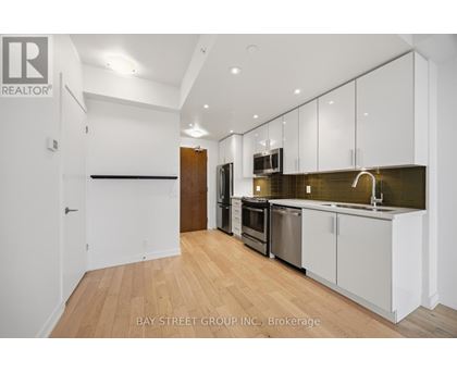 A kitchen with white cabinets and a wooden floor.