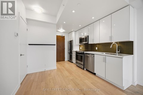 A kitchen with white cabinets and a wooden floor.