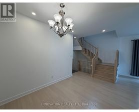 A well-lit room with a chandelier and a staircase.