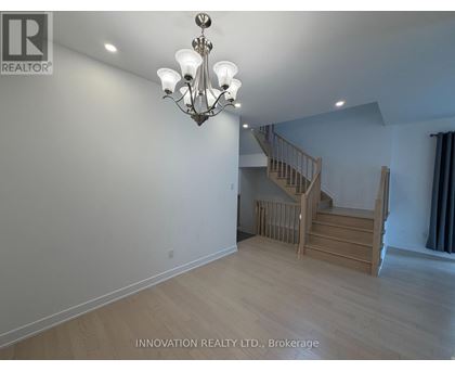 A well-lit room with a chandelier and a staircase.