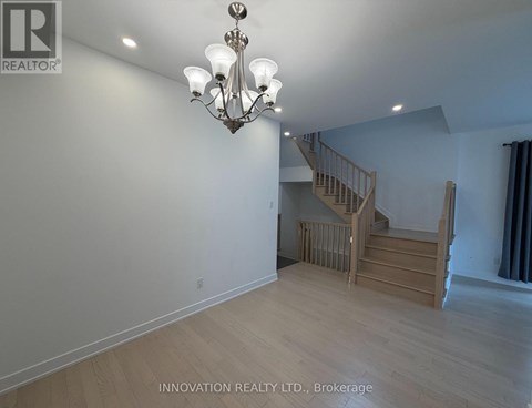 A well-lit room with a chandelier and a staircase.