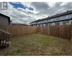 A backyard with a wooden fence and grassy area.
