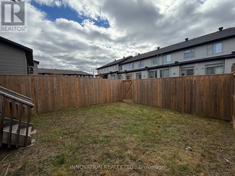 A backyard with a wooden fence and grassy area.