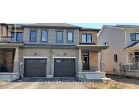A house with a grey front and black garage doors is for sale.